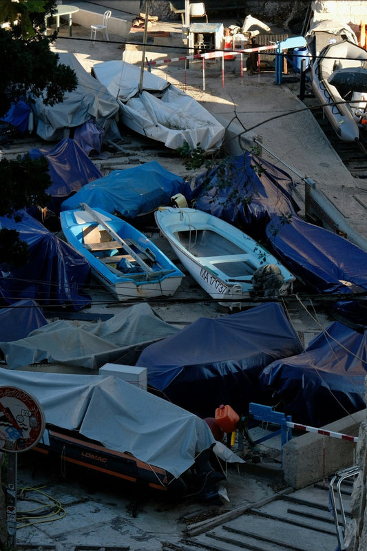Boats covered with tarps on a concrete dock