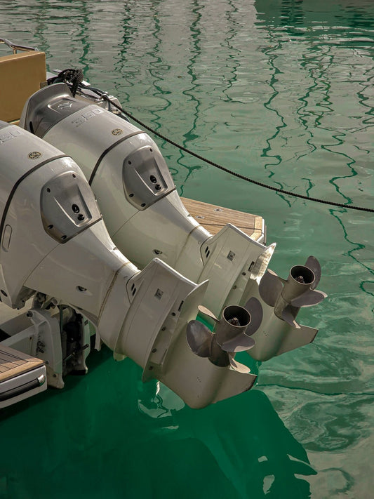 Two white outboard boat motors with propellers in green water