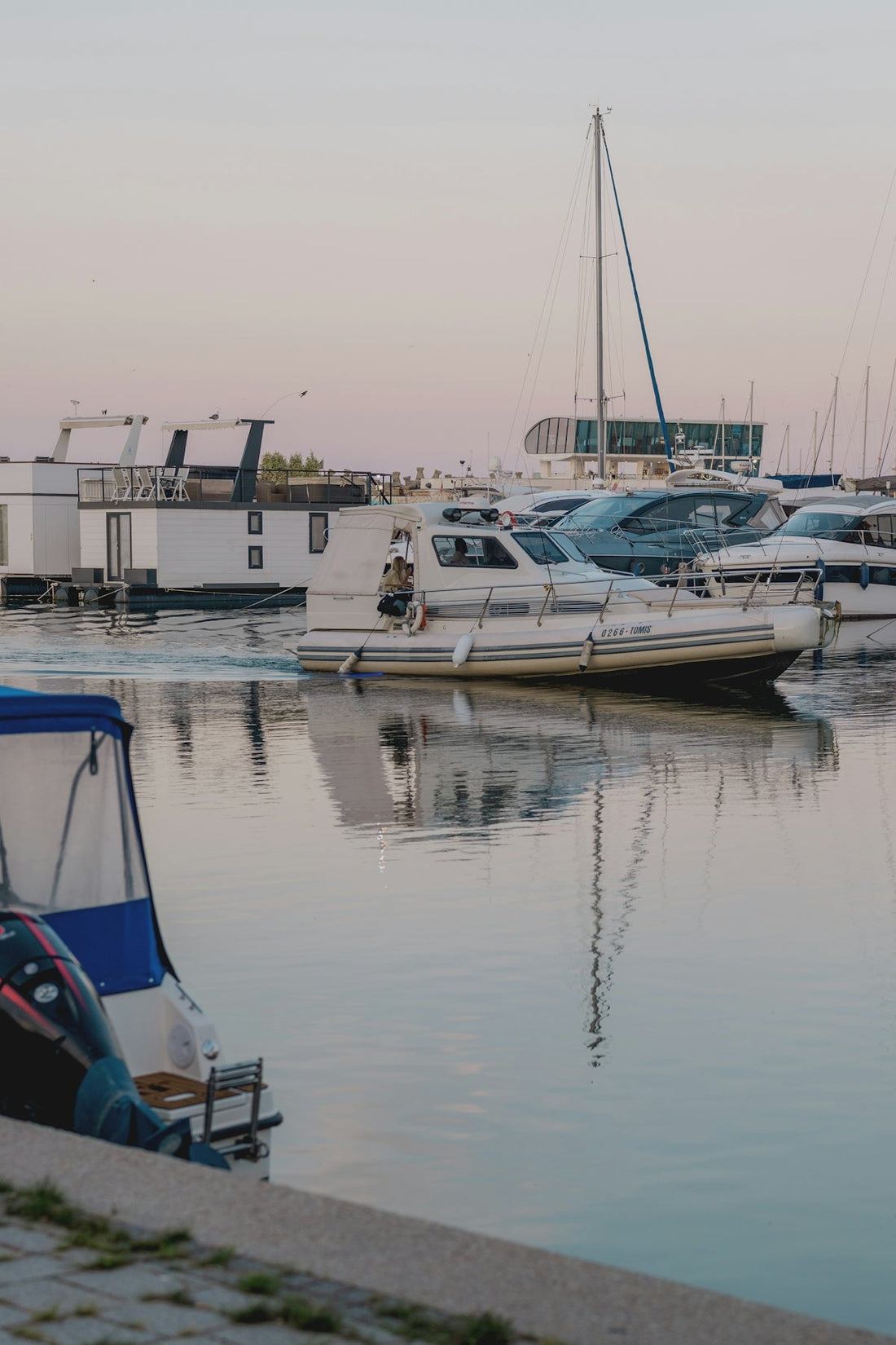 Boats docked and moving in a peaceful marina at sunset